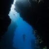 a person swimming in the water near a cave
