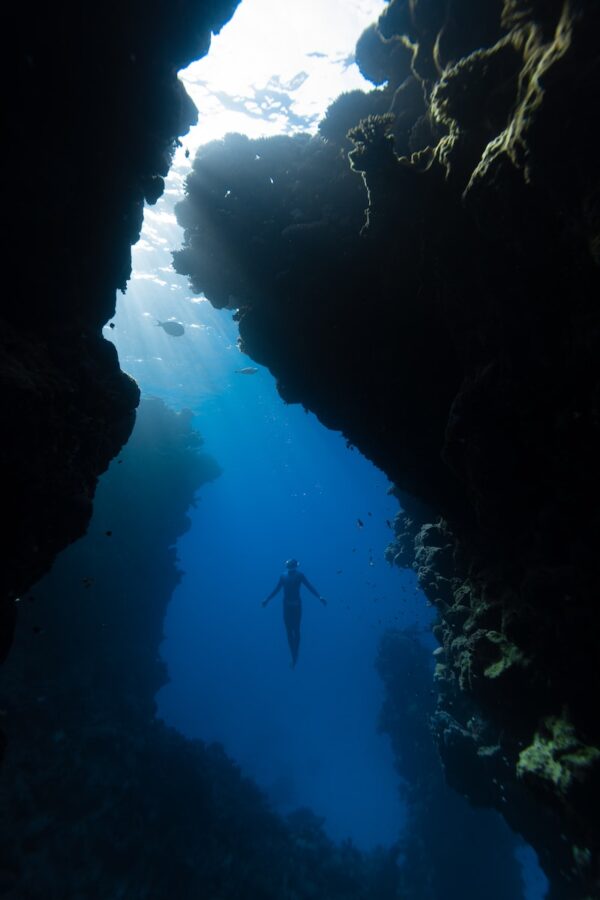 a person swimming in the water near a cave
